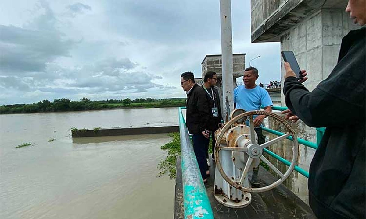 The swollen Cong Dadong Dam and its control gate are monitored during continuous rain in Arayat.