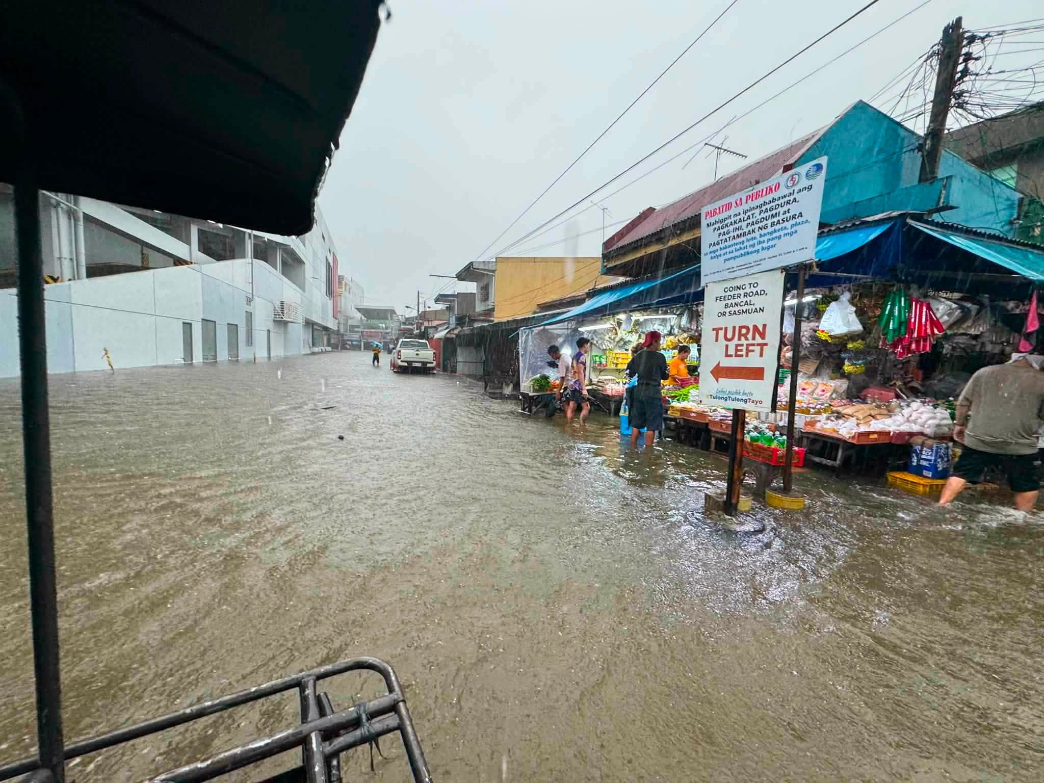 Vendors and shoppers stand in floodwater inside Guagua Public Market after overnight rain and high tide.
