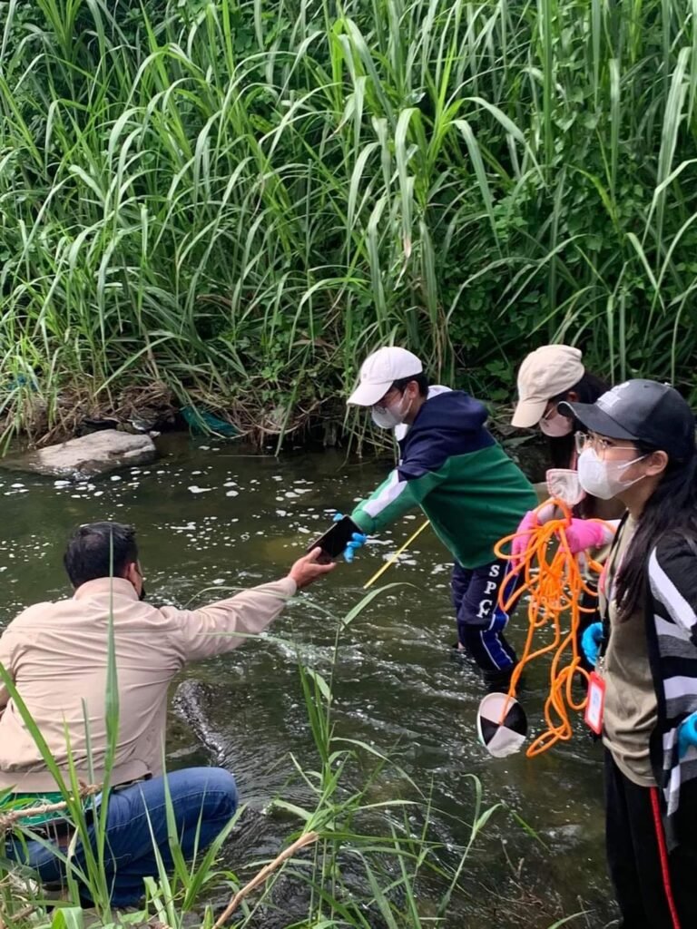 A field team wades into Sapang Balen Creek to test the water and document the condition of the Mabalacat waterway.