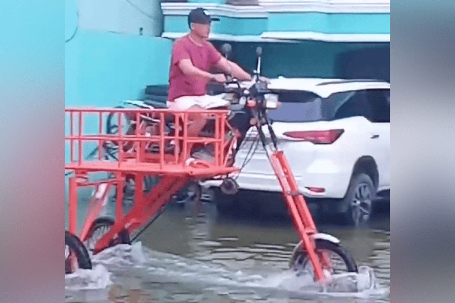 A modified elevated tricycle moves through deep floodwater on a road in Macabebe.