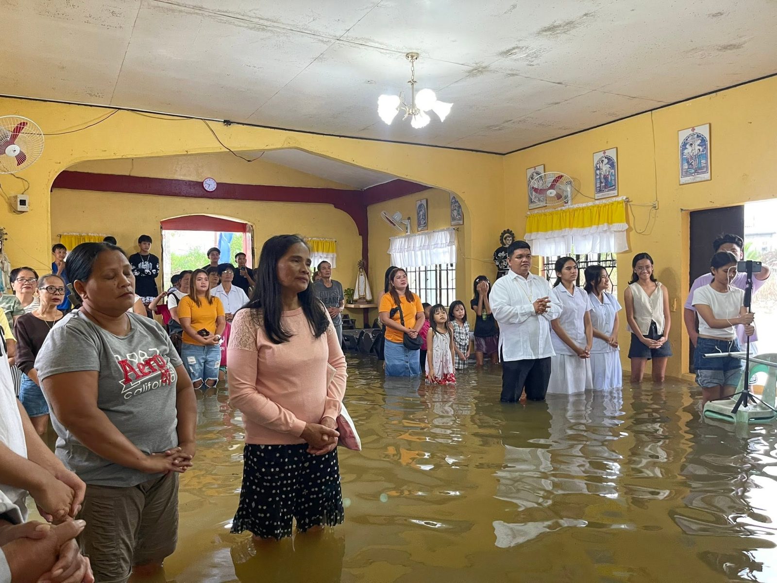 Residents attend Mass while standing in knee-deep floodwater inside Iscundo Chapel in Masantol.